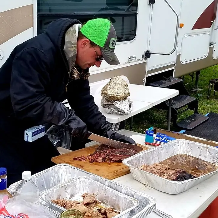 Smokey Dave slicing BBQ into foil pans at an event