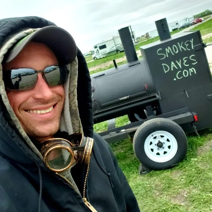 Smokey Dave smiling in front of his smoker